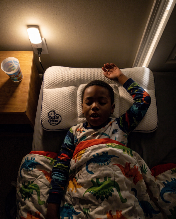 A boy asleep on the Little Otter pillow, seen from above