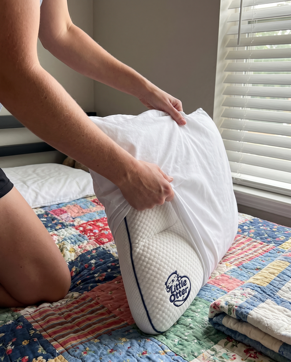 Hands fitting the cotton cover onto the Little Otter pillow on a twin bed