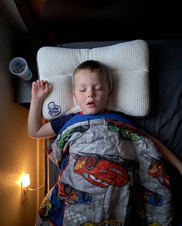 A young boy asleep on the Little Otter pillow, seen from above