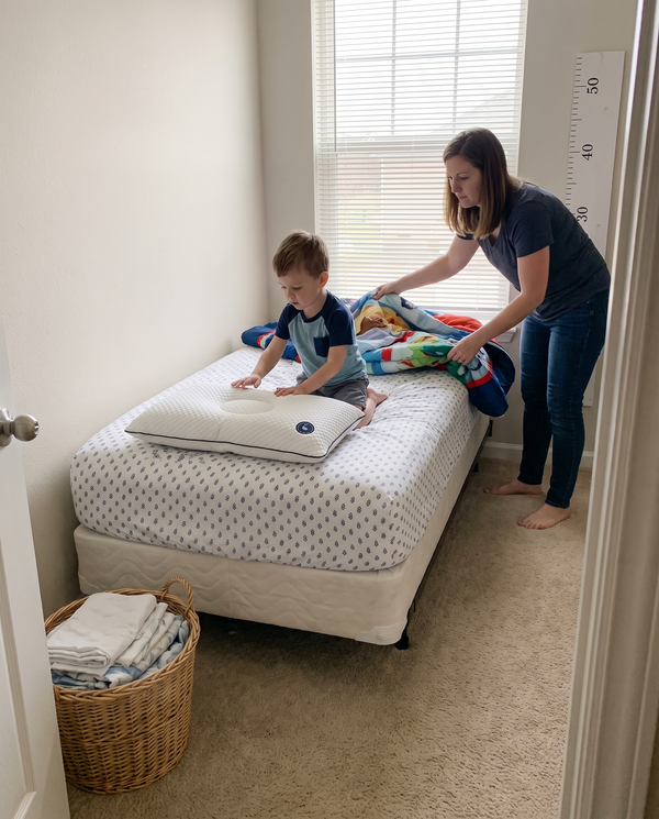 A mother and her young son making the bed, the Little Otter pillow in place